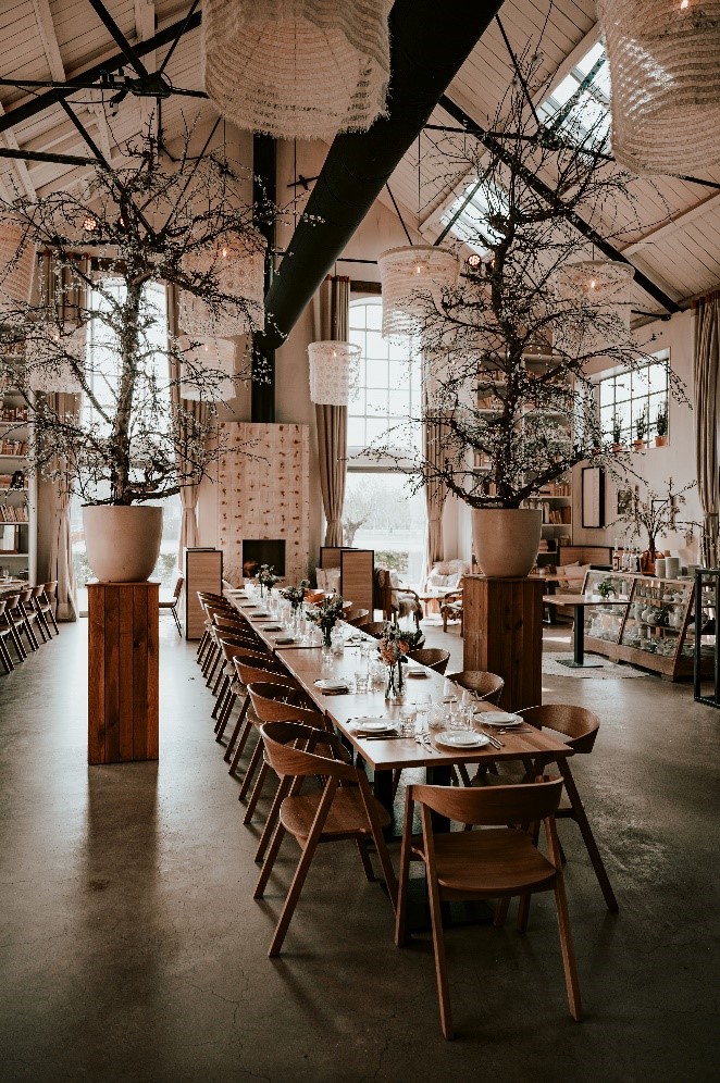 Lange gedekte dinertafel in het Centraal Ketelhuis in Amersfoort, met houten stoelen, bloemstukken en industriële details.
